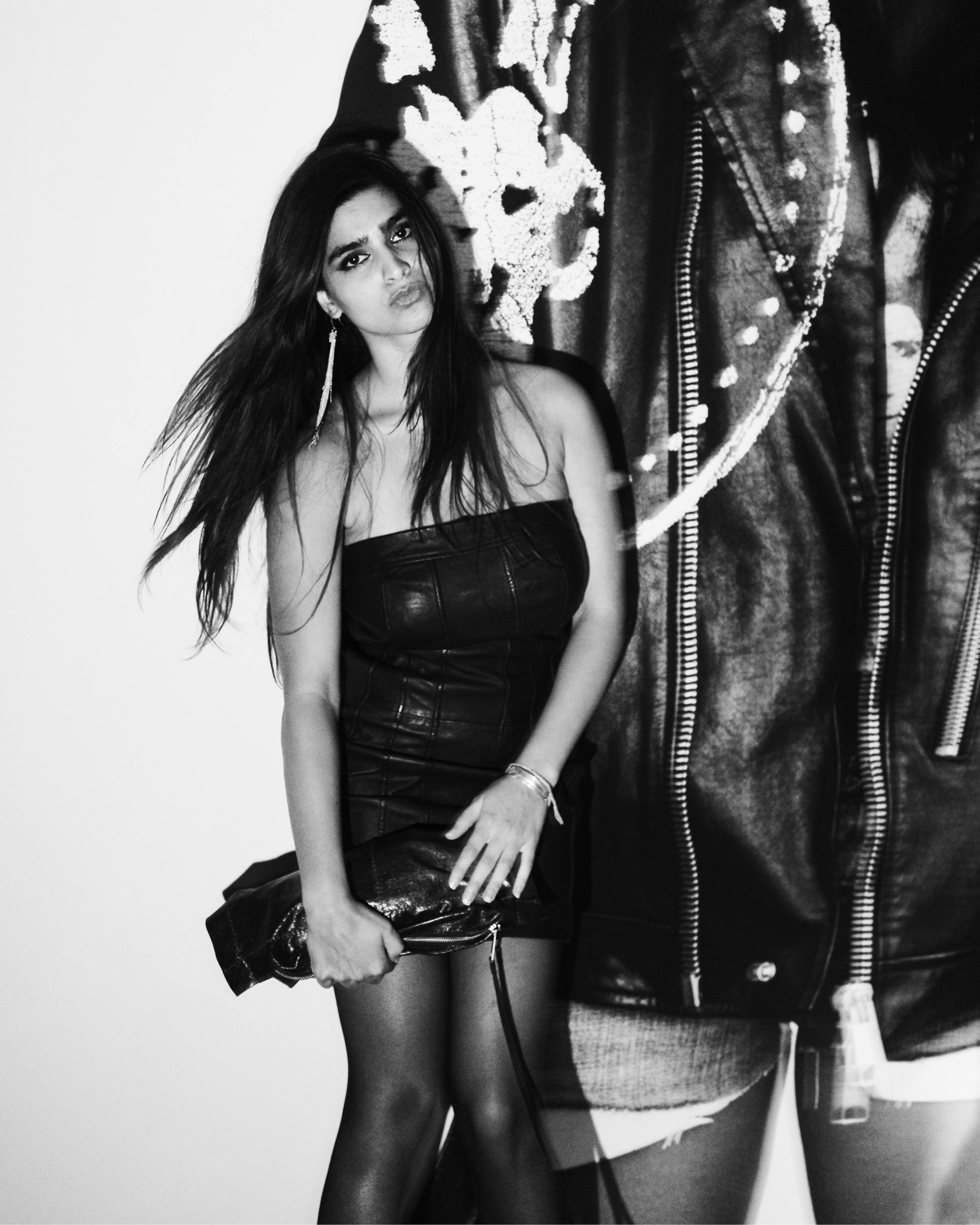 Black-and-white portrait of a guest posing beside oversized AllSaints campaign imagery at the Autumn Winter 26 Launch Party.