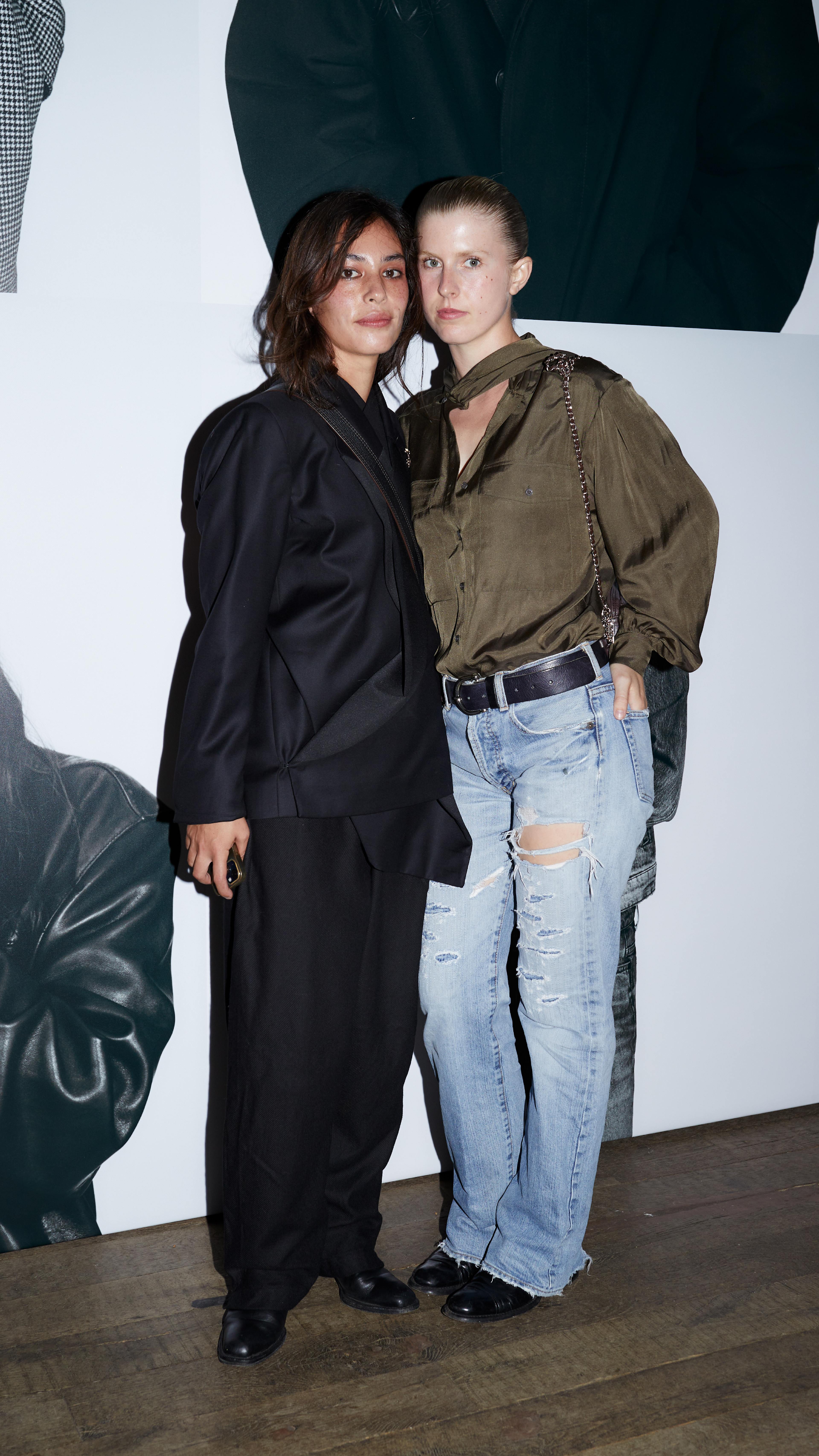 Two guests posing together in dark tailoring and casual separates at the AllSaints Autumn Winter 26 Launch Party.