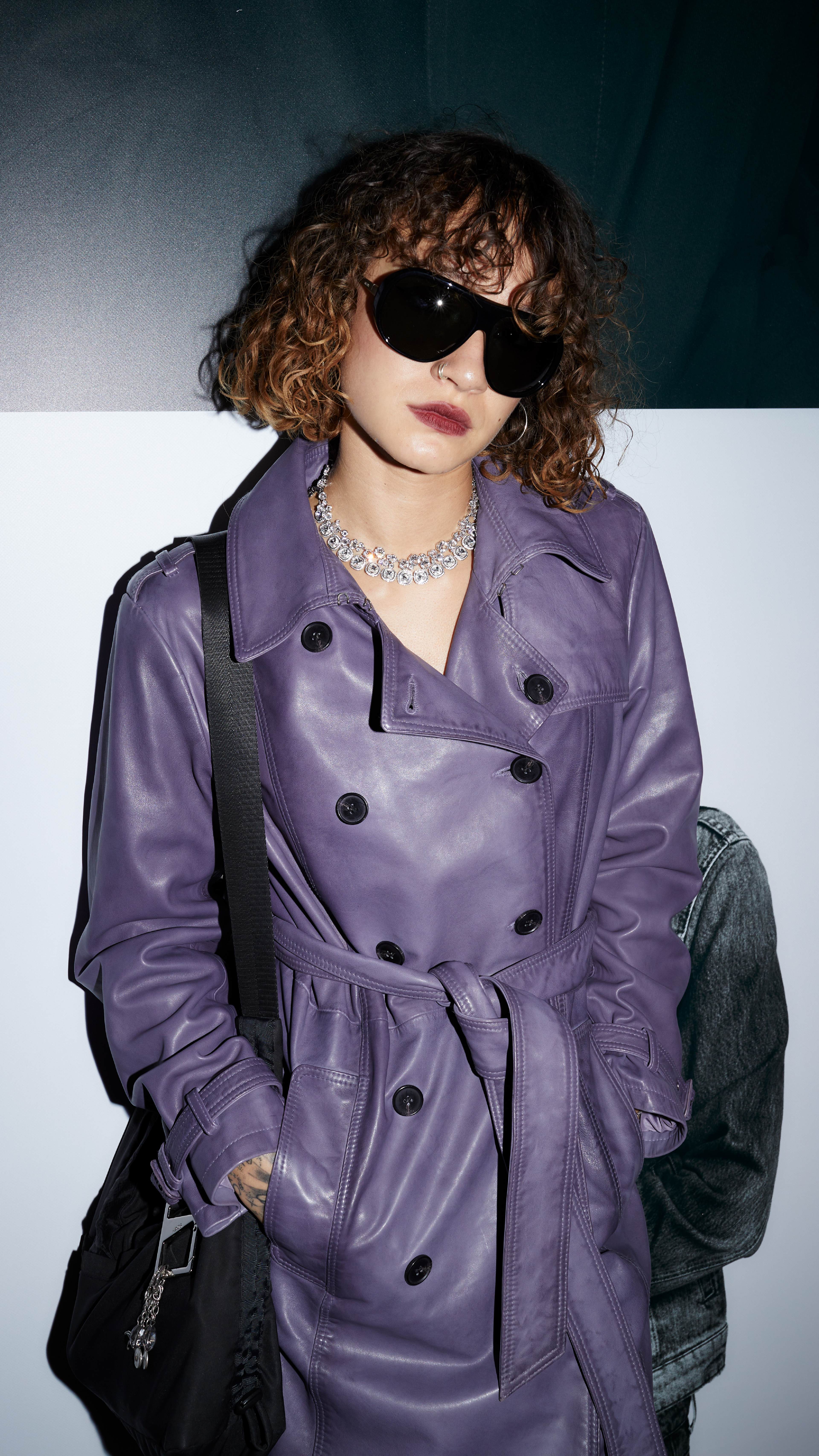 Guest wearing sunglasses and a purple leather trench coat at the AllSaints Autumn Winter 26 Launch Party.